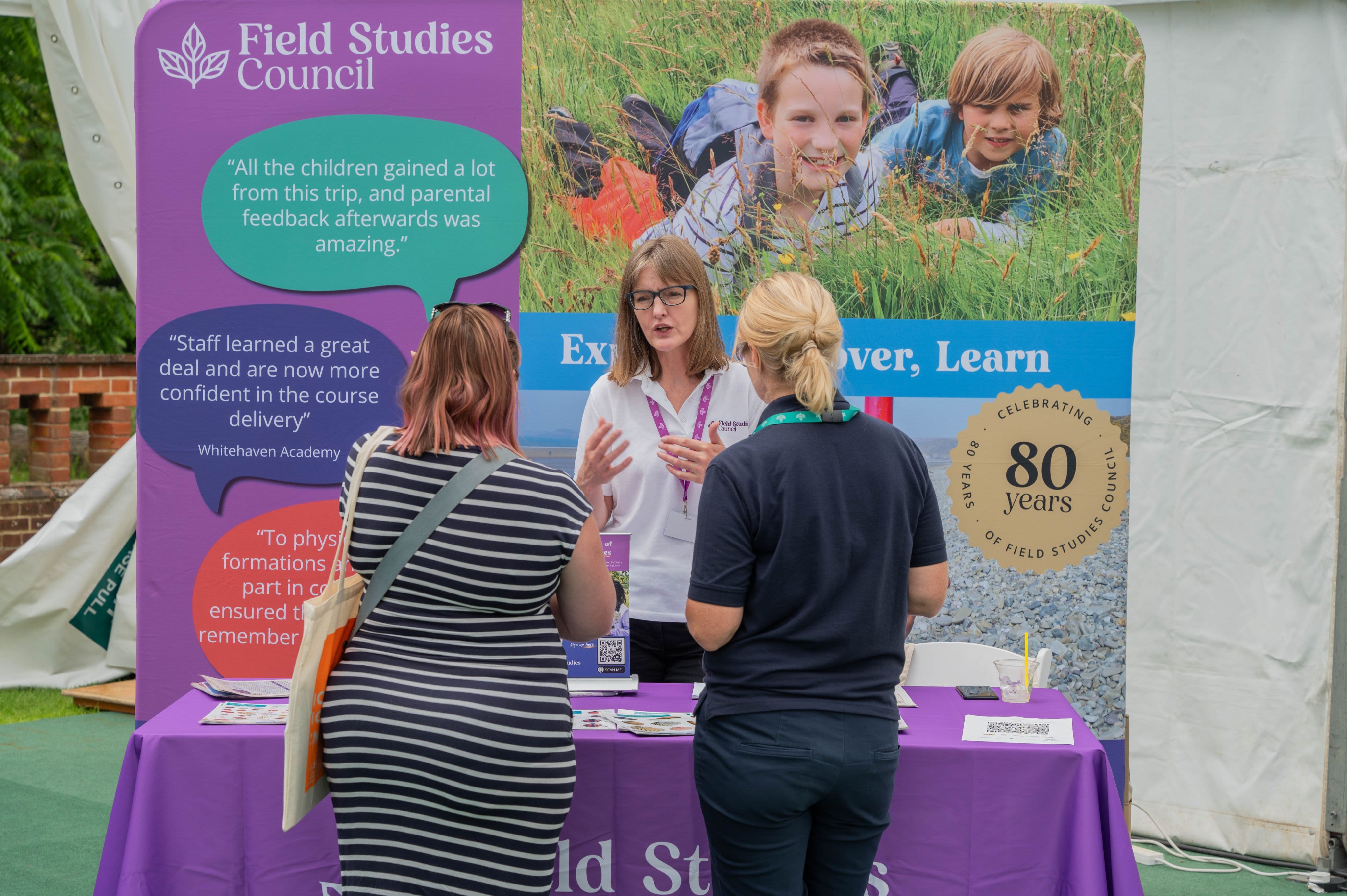 Three people talking at The Field Studies Council exhibition stand