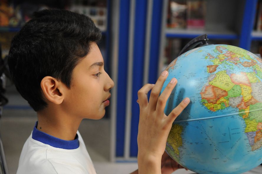 side profile of a young male student inspecting a globe