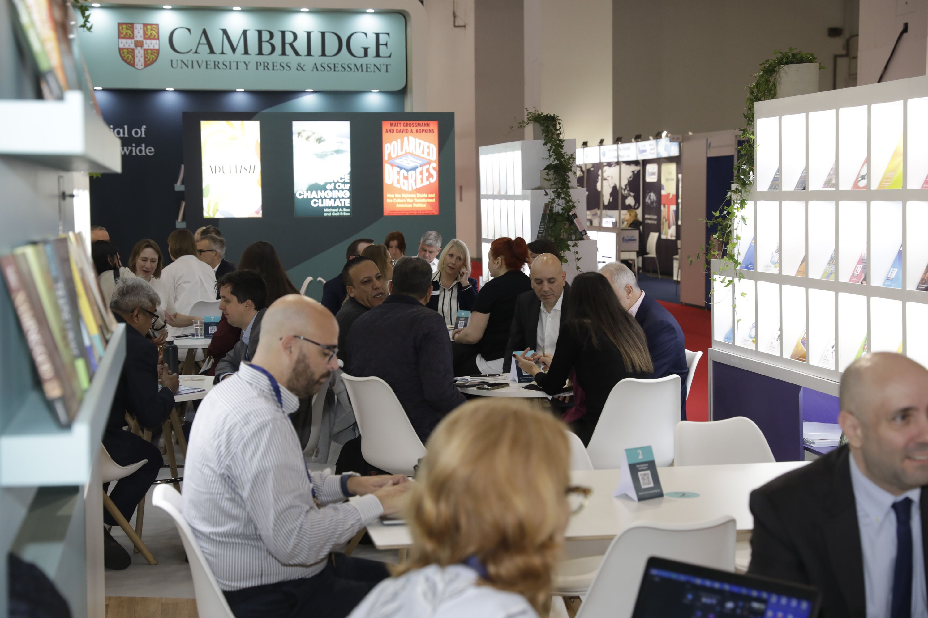 Visitors sitting at Cambridge zone atg Frankfurt book fair, reading books published by Cambridge University Press