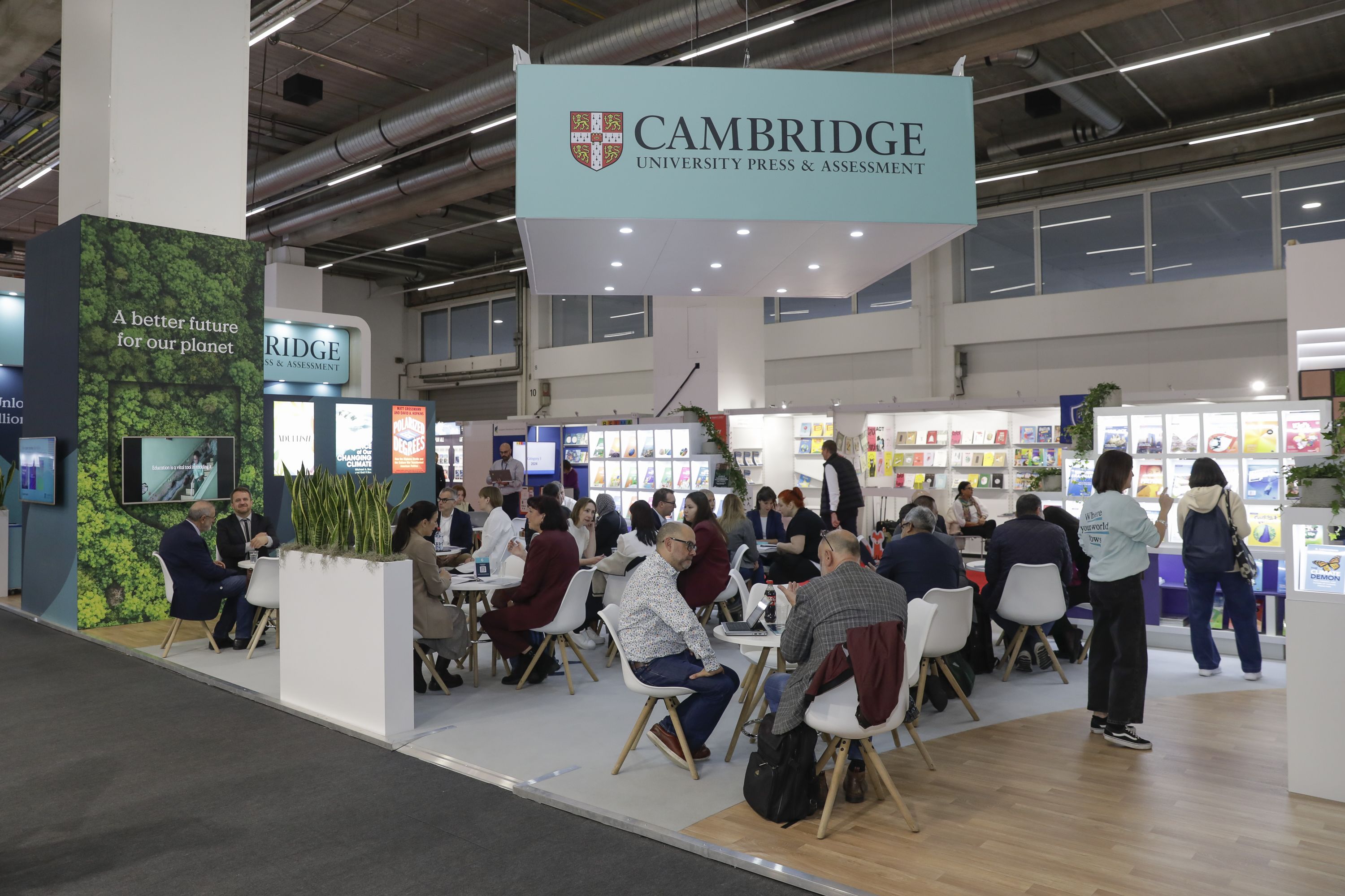 Visitors sitting at Cambridge zone atg Frankfurt book fair, reading books published by Cambridge University Press