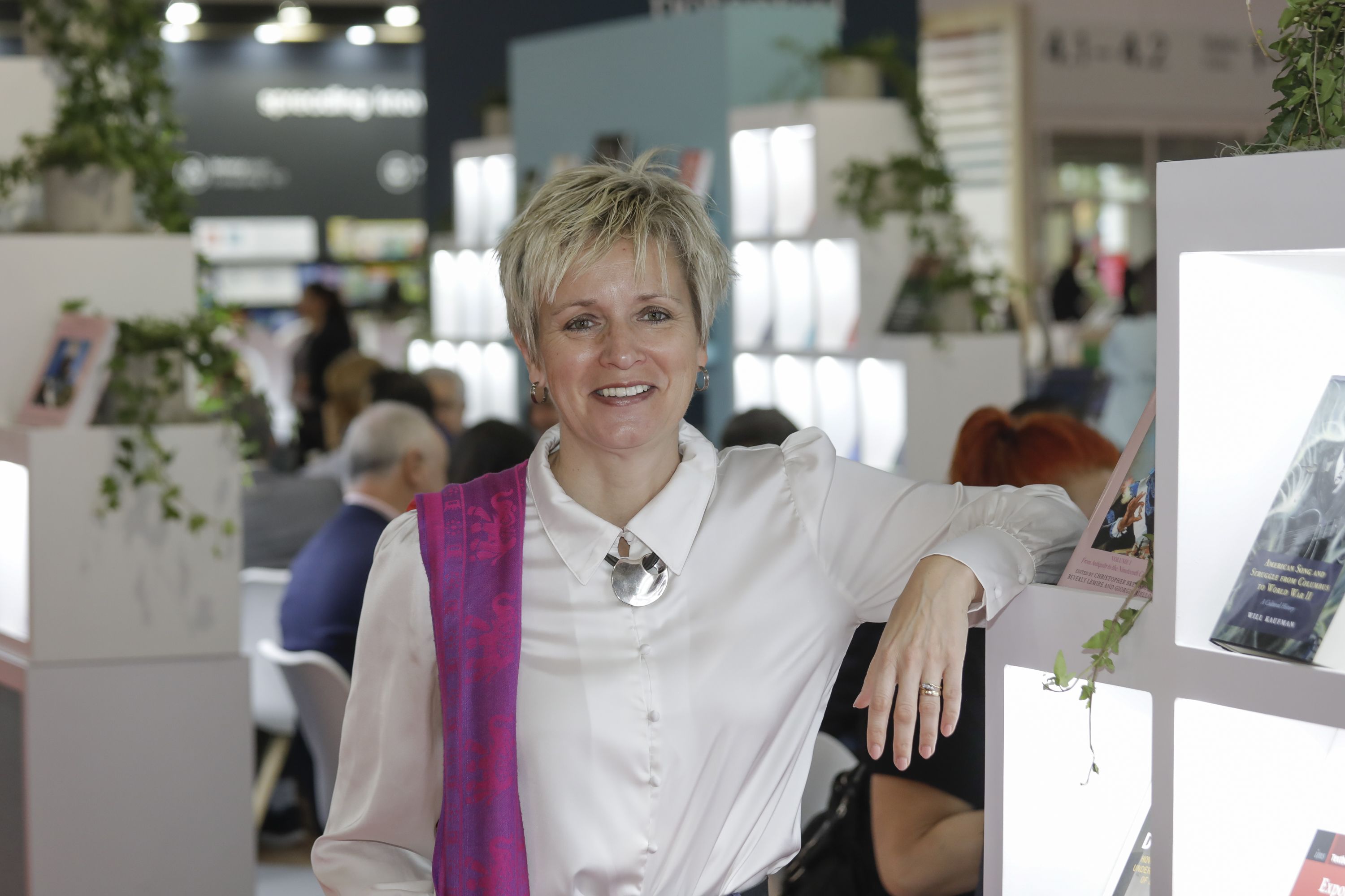 Mandy Hill, Managing Director of Cambridge University Press, standing next to the book shelf at Frankfurt Book Fair